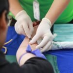 A healthcare professional administering an injection to a patient's arm during a medical procedure.